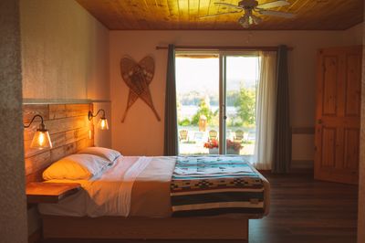 Chambre avec lit, porte-patio ouverte sur la véranda et vue directe sur le lac Saguay